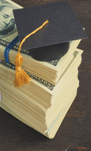 Small Graduation hat on top of Dollar Bills
