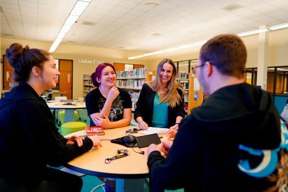 Students around a table sitting and talking